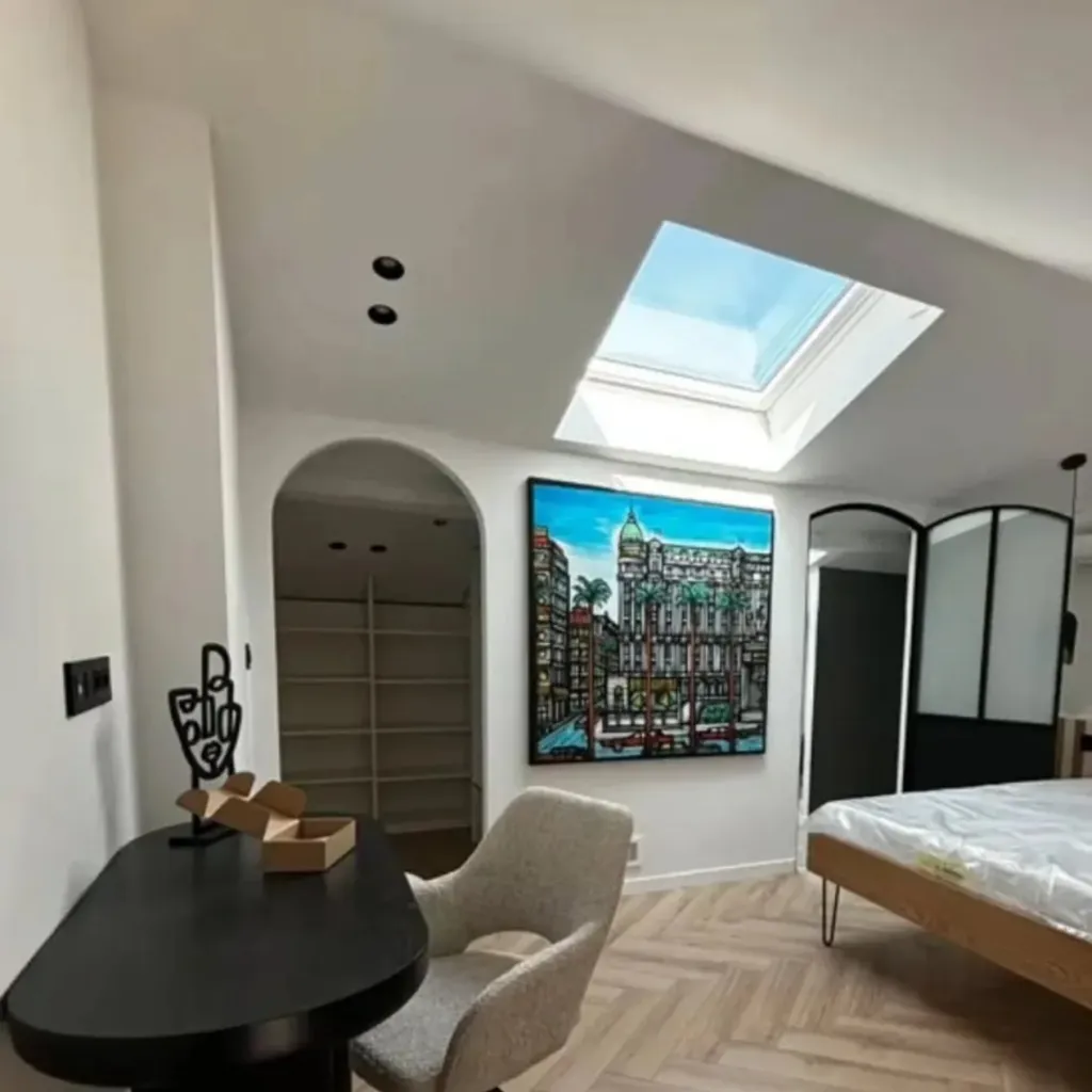 Chambre sous combles avec velux, spots encastrés, arche, verrière noire et parquet à chevrons.